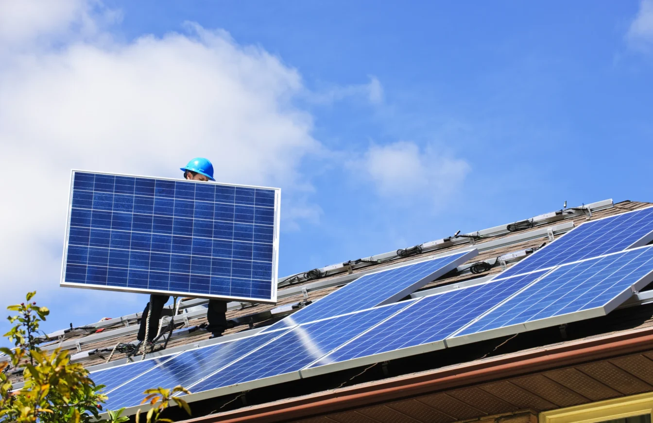 Instalador fotovoltaico realizando la instalación de placas solares en el tejado de una vivienda
