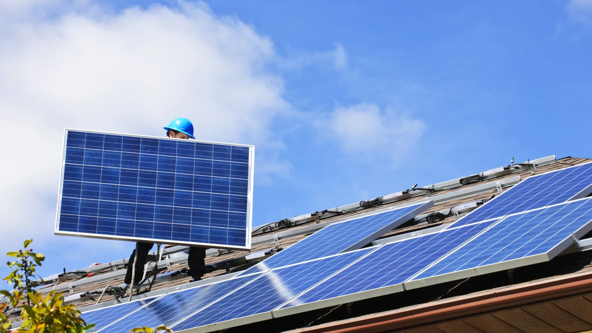 Instalador fotovoltaico realizando la instalación de placas solares en el tejado de una vivienda